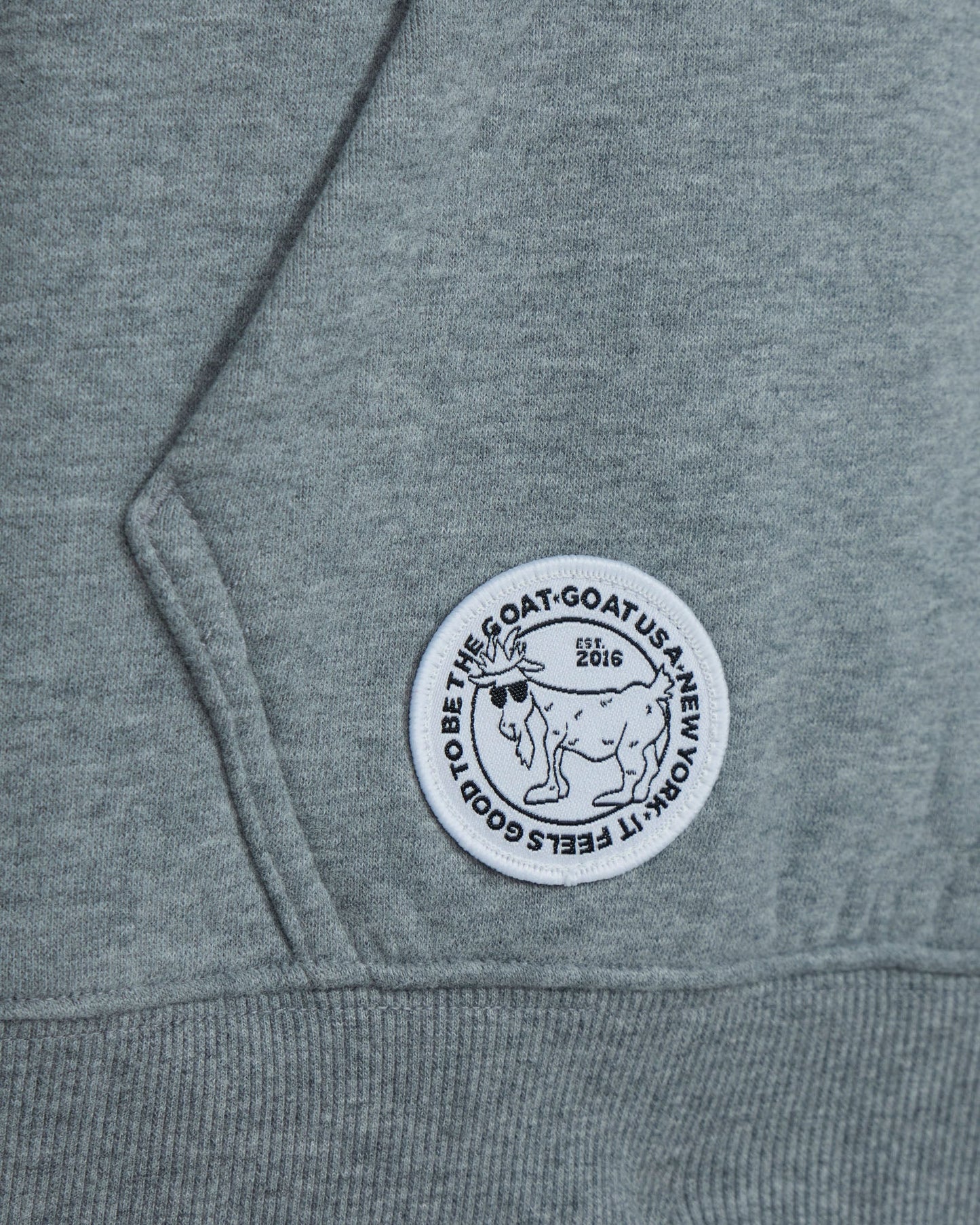 Gray sweatshirt with a circular logo featuring a goat and text on the sleeve.