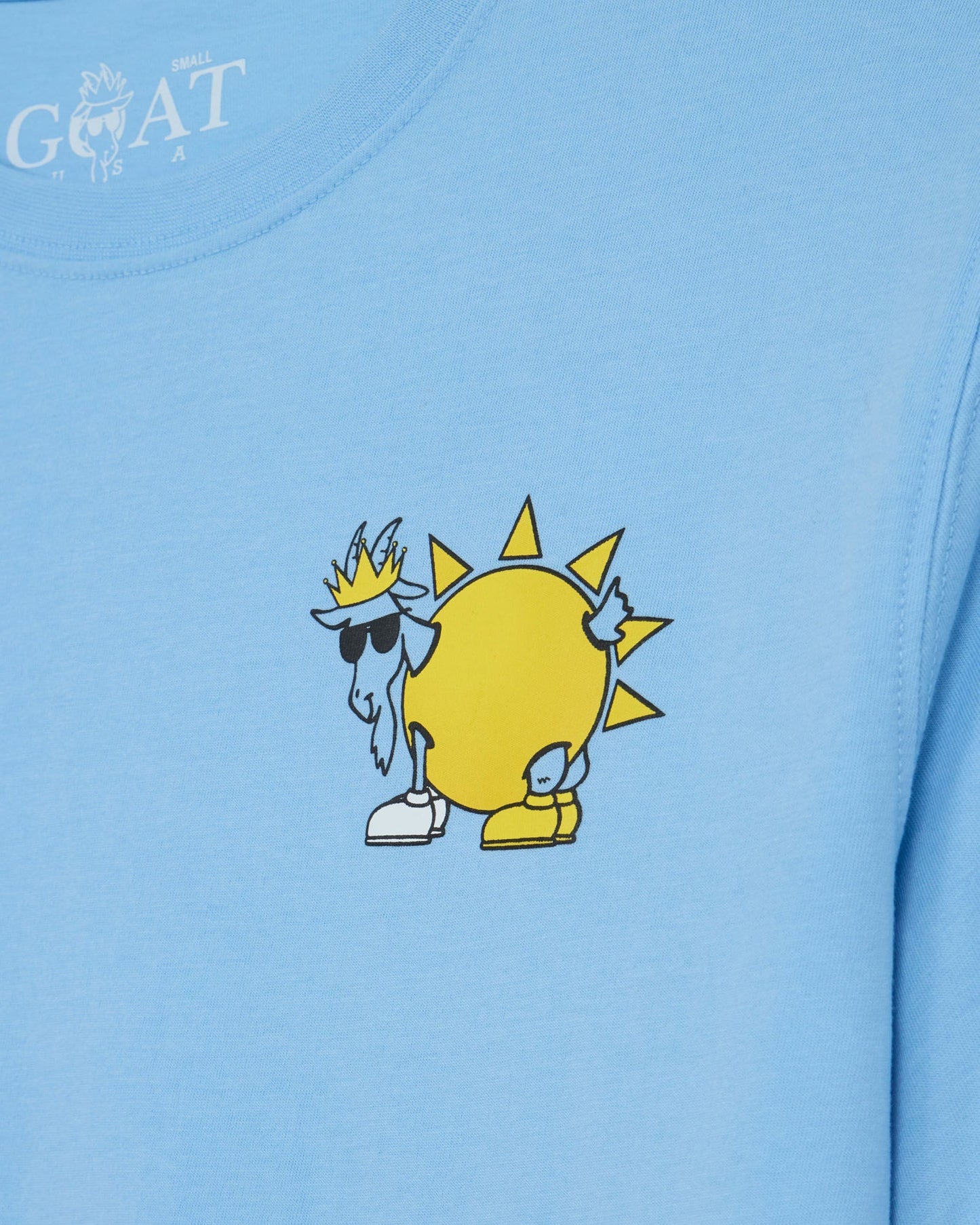 Light blue t-shirt with a cartoon goat wearing sunglasses and a crown on a yellow circle design.