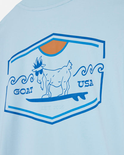 Light blue t-shirt with a graphic of a goat on a surfboard and 'GOAT USA' text, on a light blue background.#color_delicate-blue