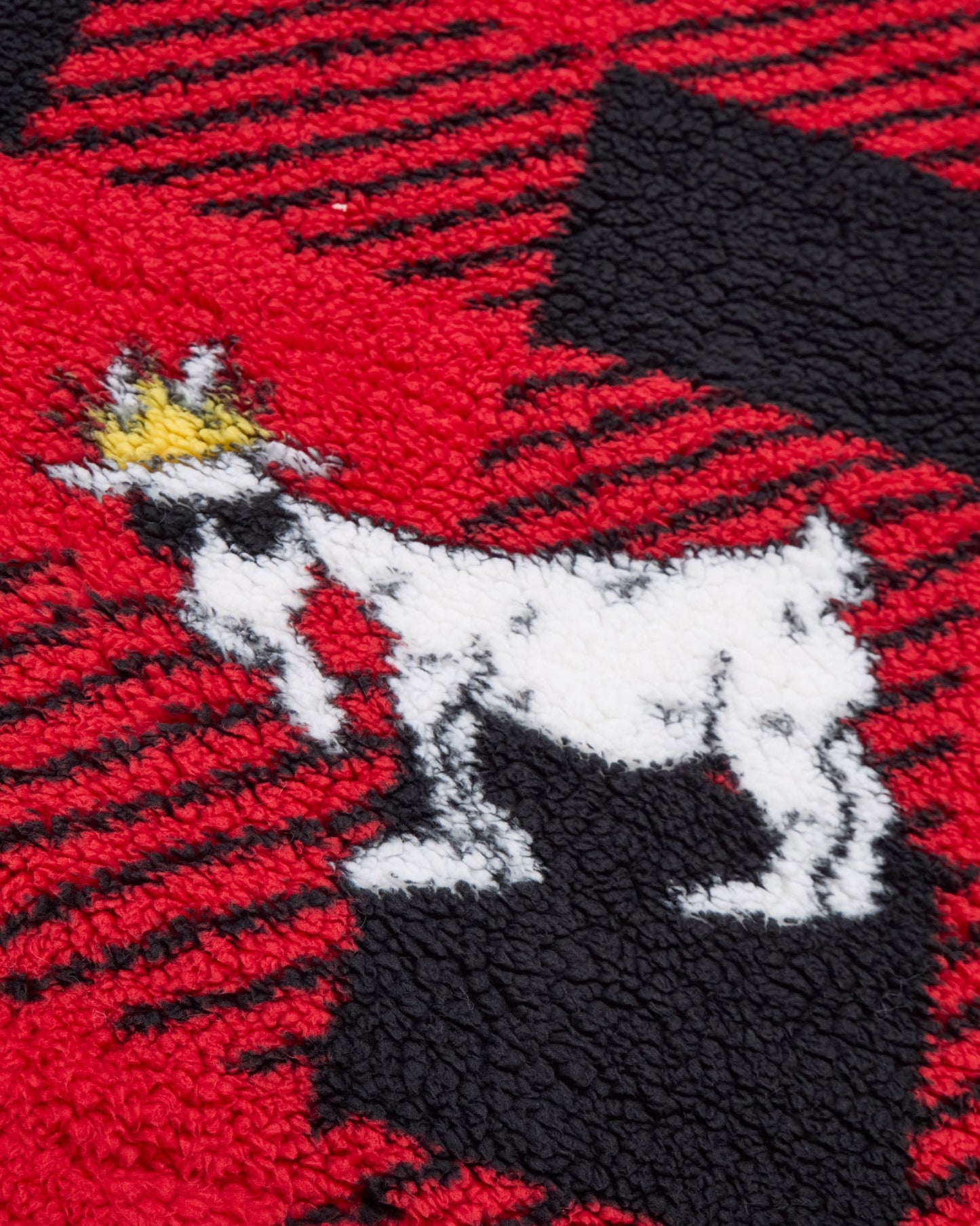 Embroidered design of a goat with a crown on a red, black, and white checkered fabric background.