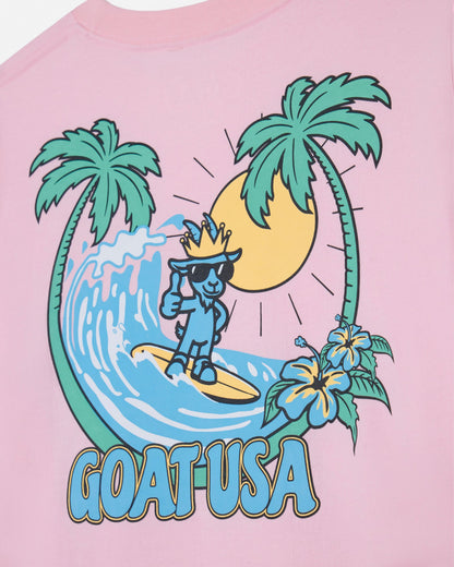 Pink t-shirt with a graphic of a character surfing, palm trees, and flowers on a pink background.