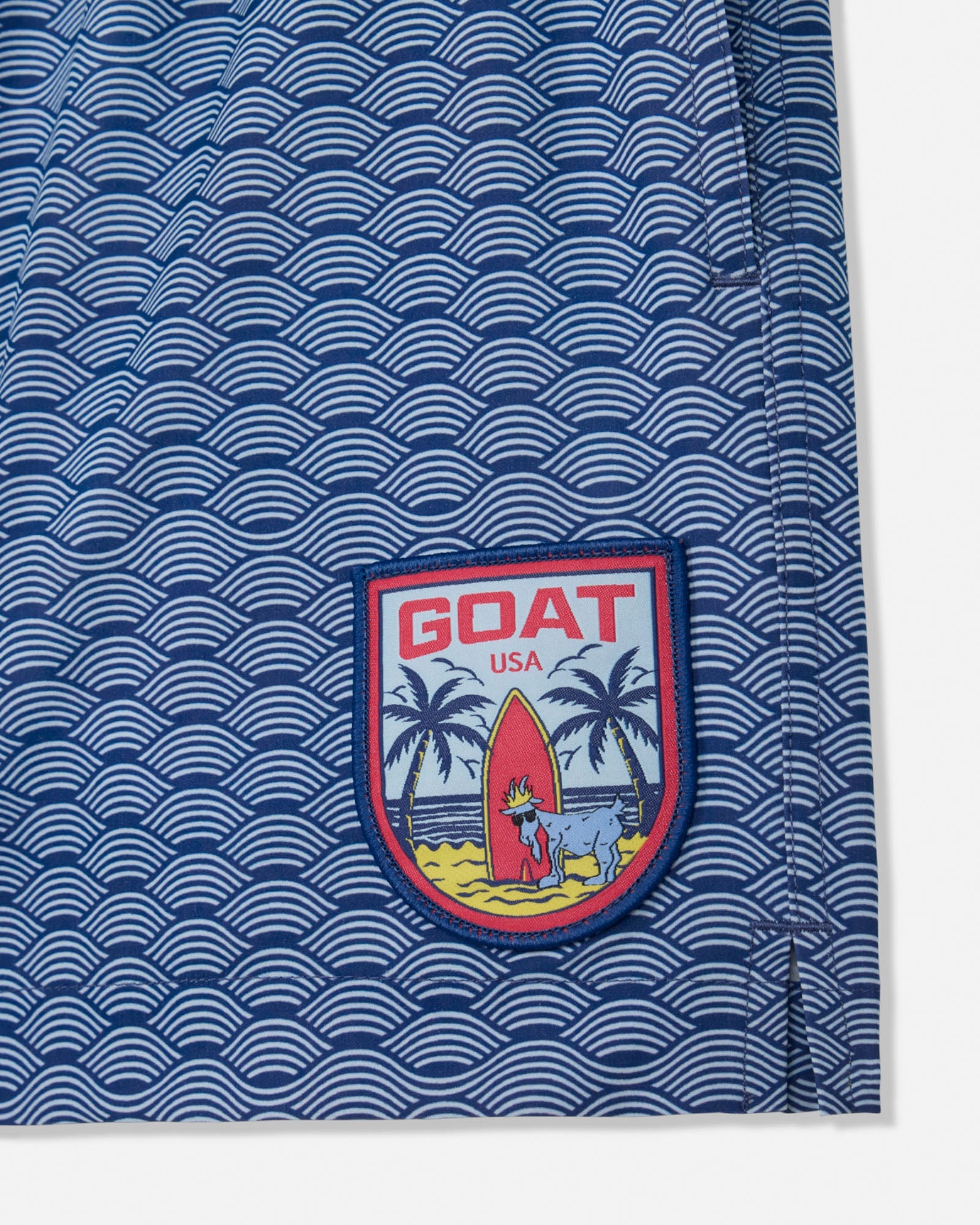Blue bathing suit with wave pattern and 'GOAT USA' logo on a white background