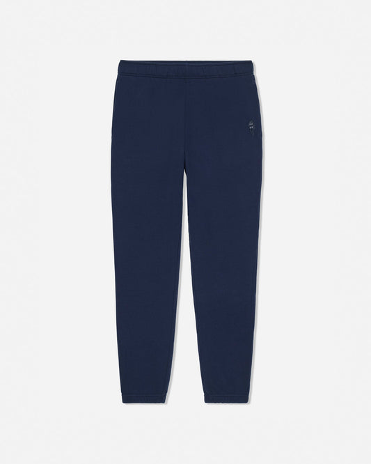 A pair of navy blue sweatpants with an elastic waistband and a small white embroidered logo on the left hip, shown against a light gray background.#color_navy-blazer