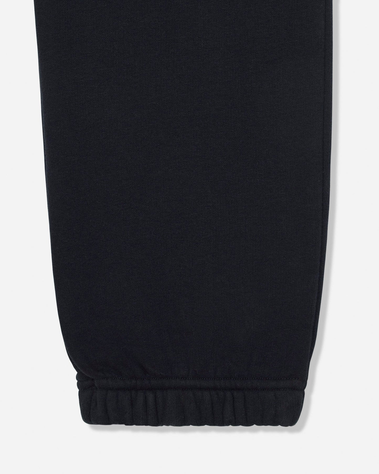 Close-up of a black fabric garment leg with an elasticized cuff, shown against a light gray background.#color_black