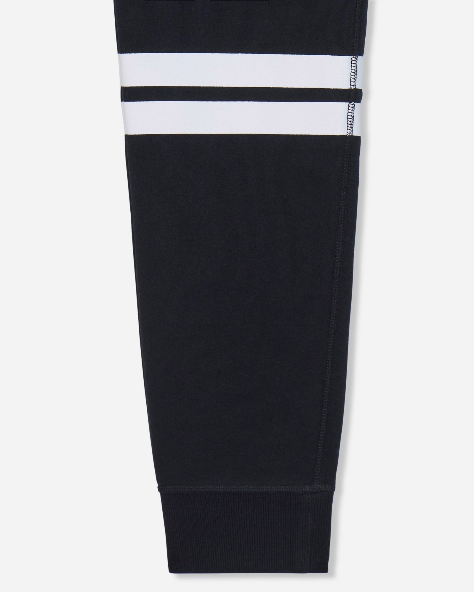 A close-up of a black garment leg with two horizontal white stripes near the upper section, shown against a light gray background.