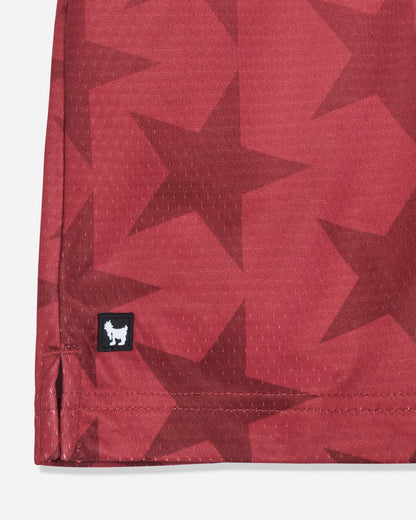Close-up of rubber patch on red mesh shorts with a star pattern#color_tomato