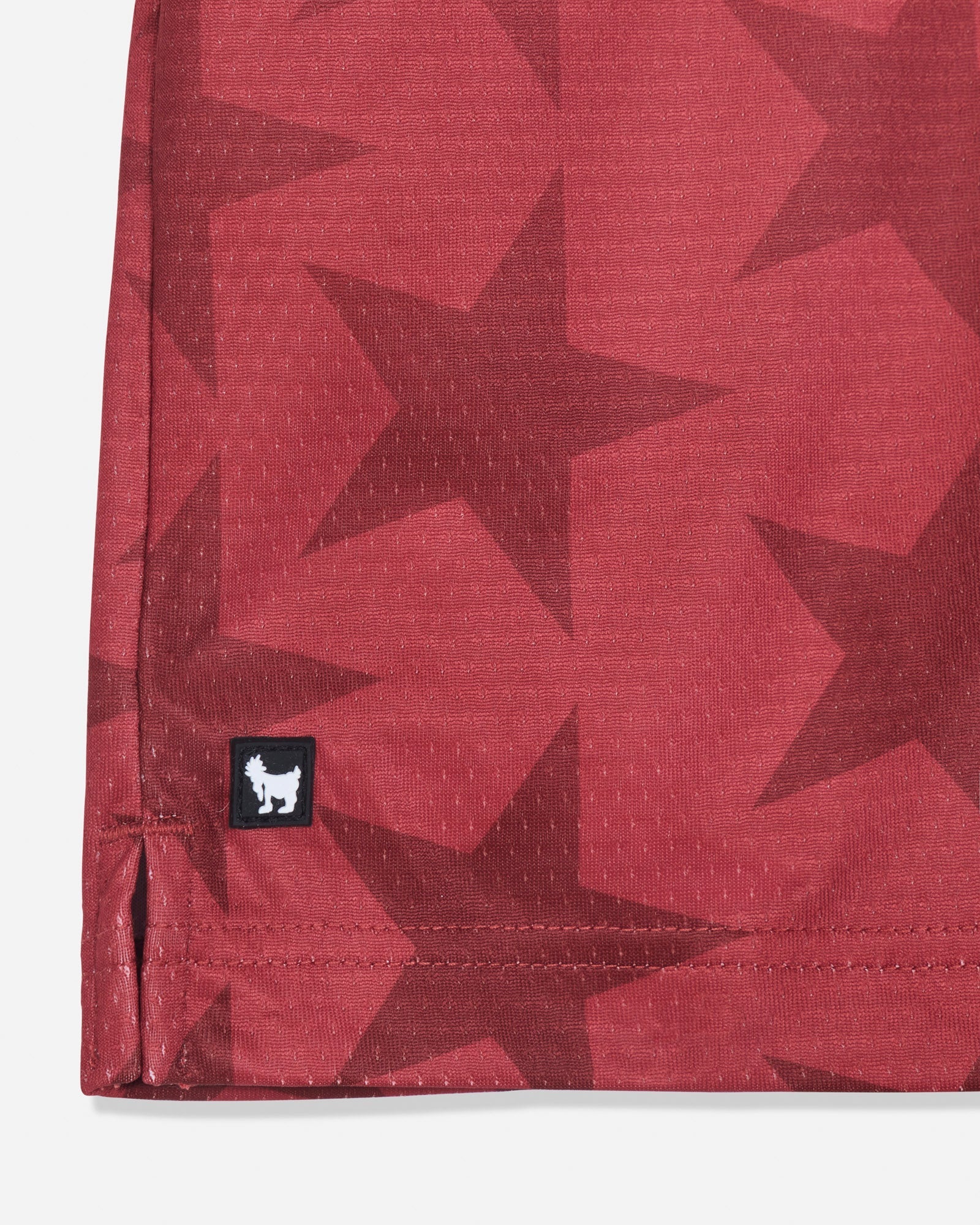 Close-up of rubber patch on red mesh shorts with a star pattern#color_tomato
