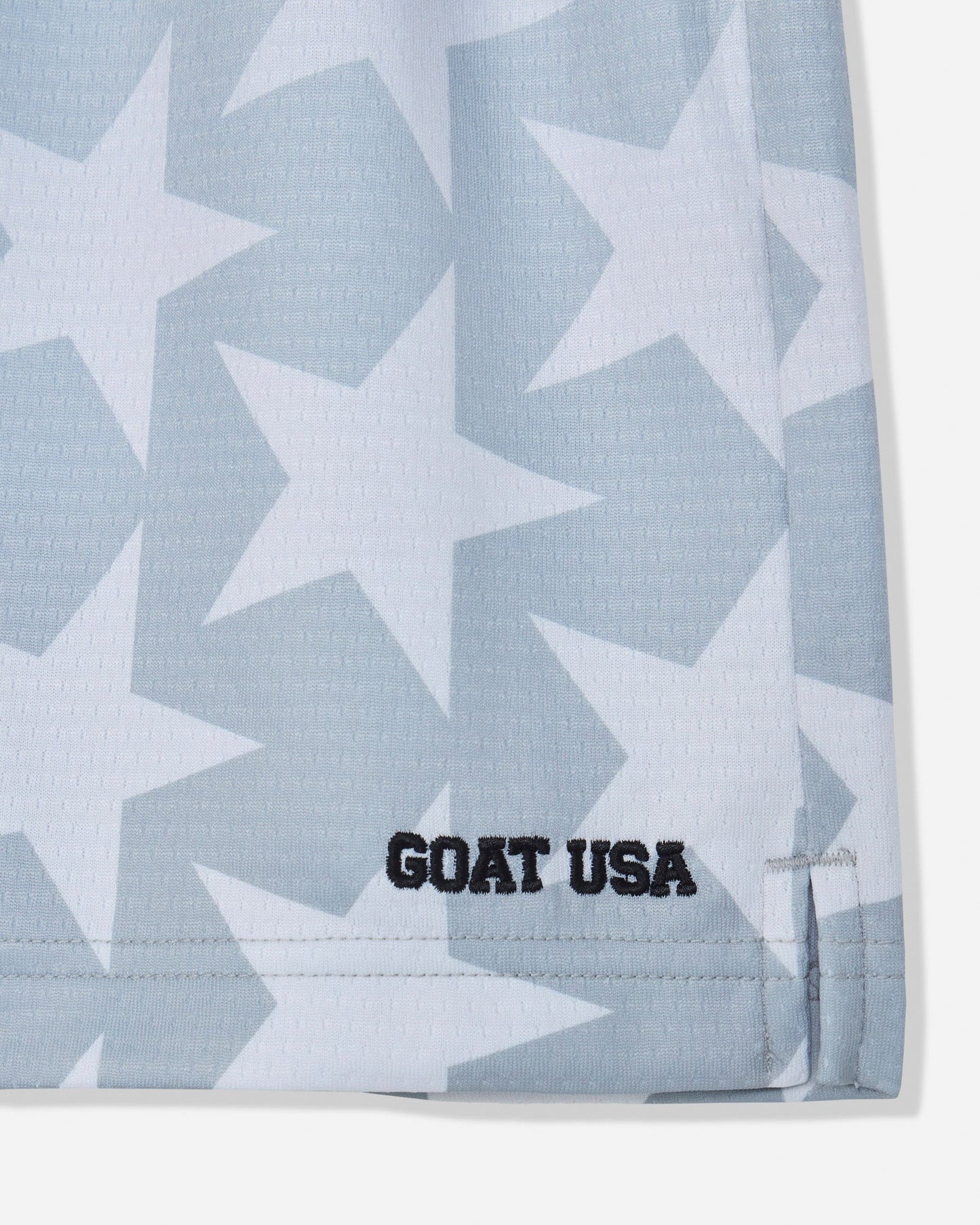 Close-up of gray mesh shorts with a star pattern and stitched 'GOAT USA' text#color_gray