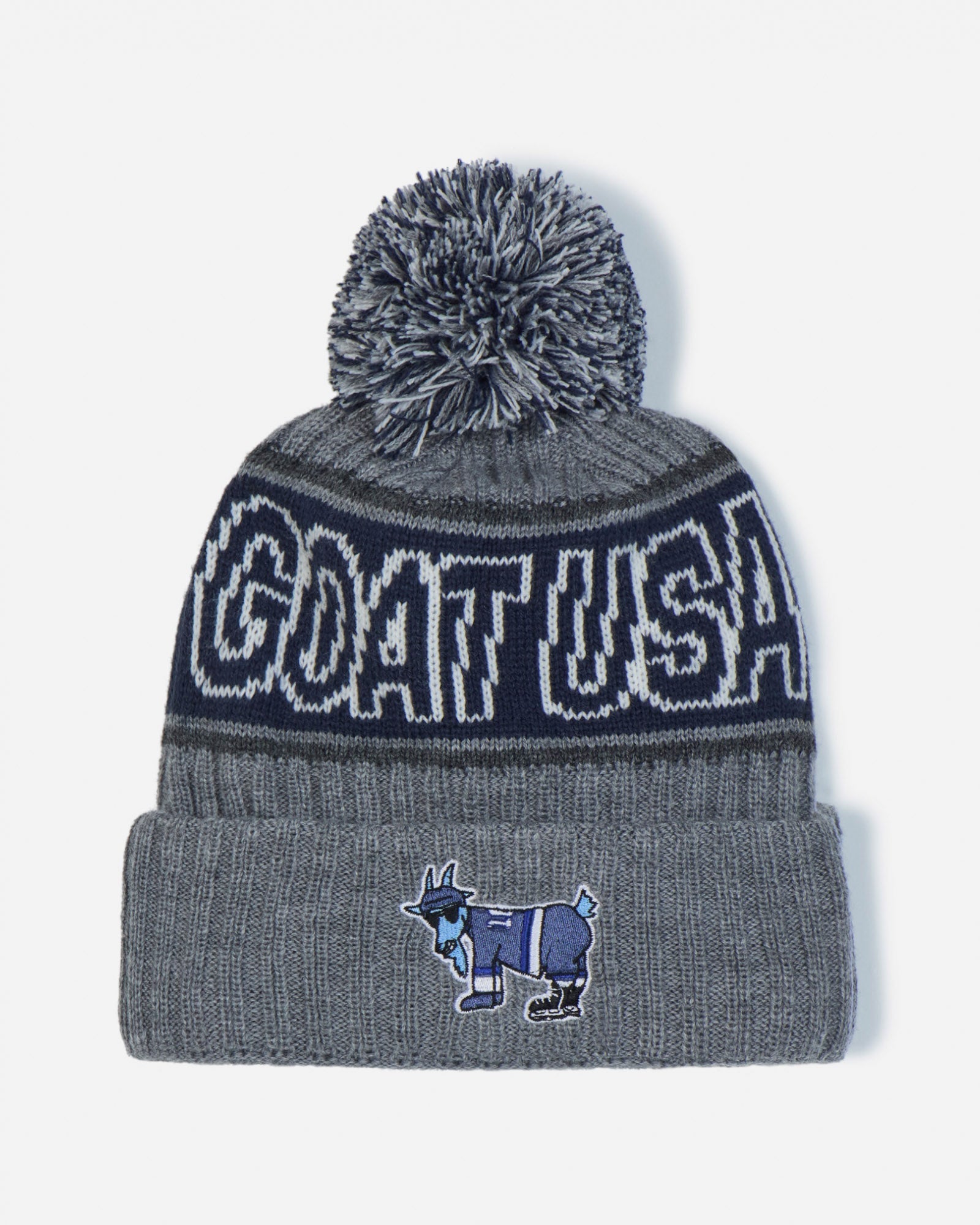 A gray and navy blue knit beanie with a gray pom-pom, featuring 'GOAT USA' in white lettering on a navy band and a small goat mascot patch on the front cuff.