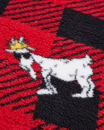 Embroidered design of a goat with a crown on a red, black, and white checkered fabric background.