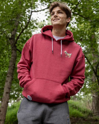 Person wearing a red hoodie with a small design, standing in a forest.#color_cardinal