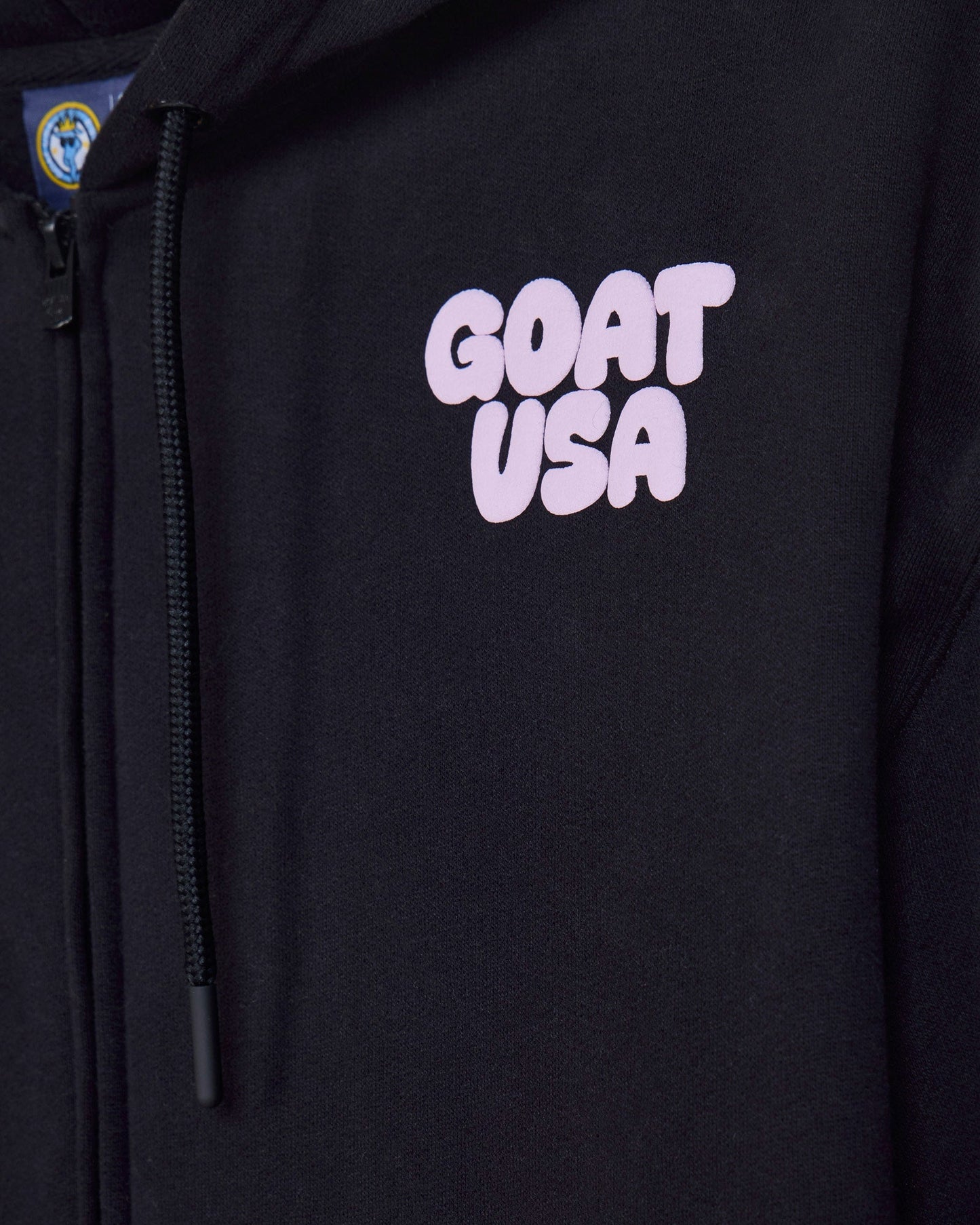 Close-up of front of black hoodie with 'GOAT USA' left-chest logo text#color_black