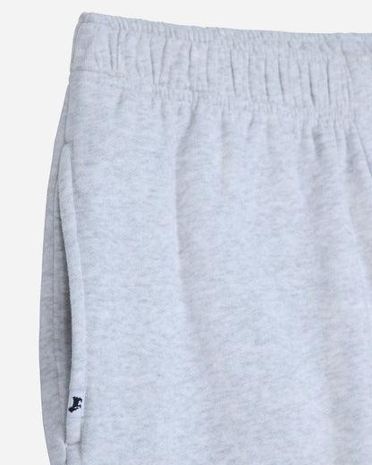 Close-up of light heather gray sweatpants showing the elastic waistband and side seam with a small black embroidered logo near the hem.#color_pale-gray-heather