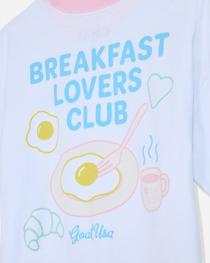 Close-up of white oversized t-shirt that says 'Breakfast Lovers Club' with various breakfast items
