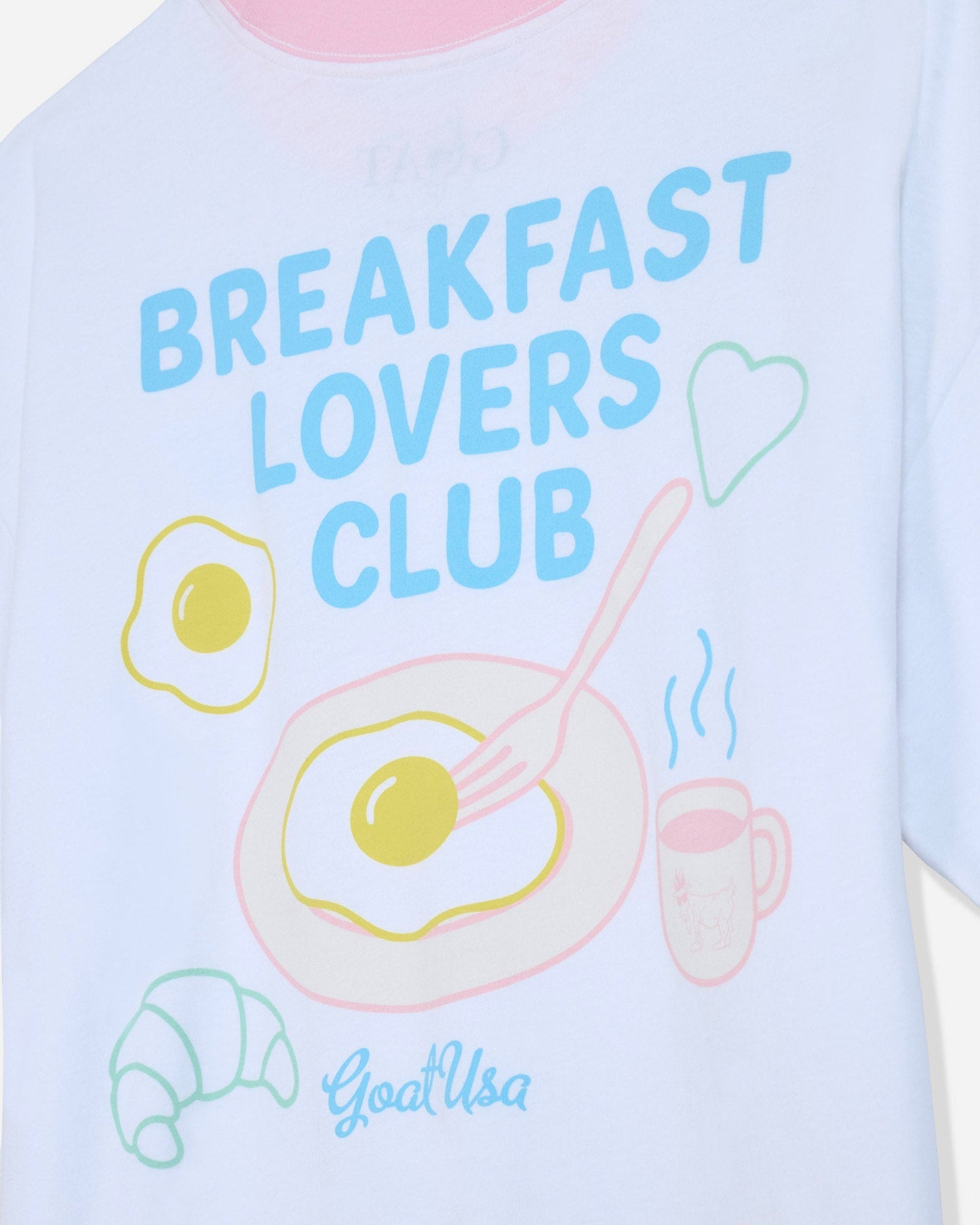 Close-up of white oversized t-shirt that says 'Breakfast Lovers Club' with various breakfast items
