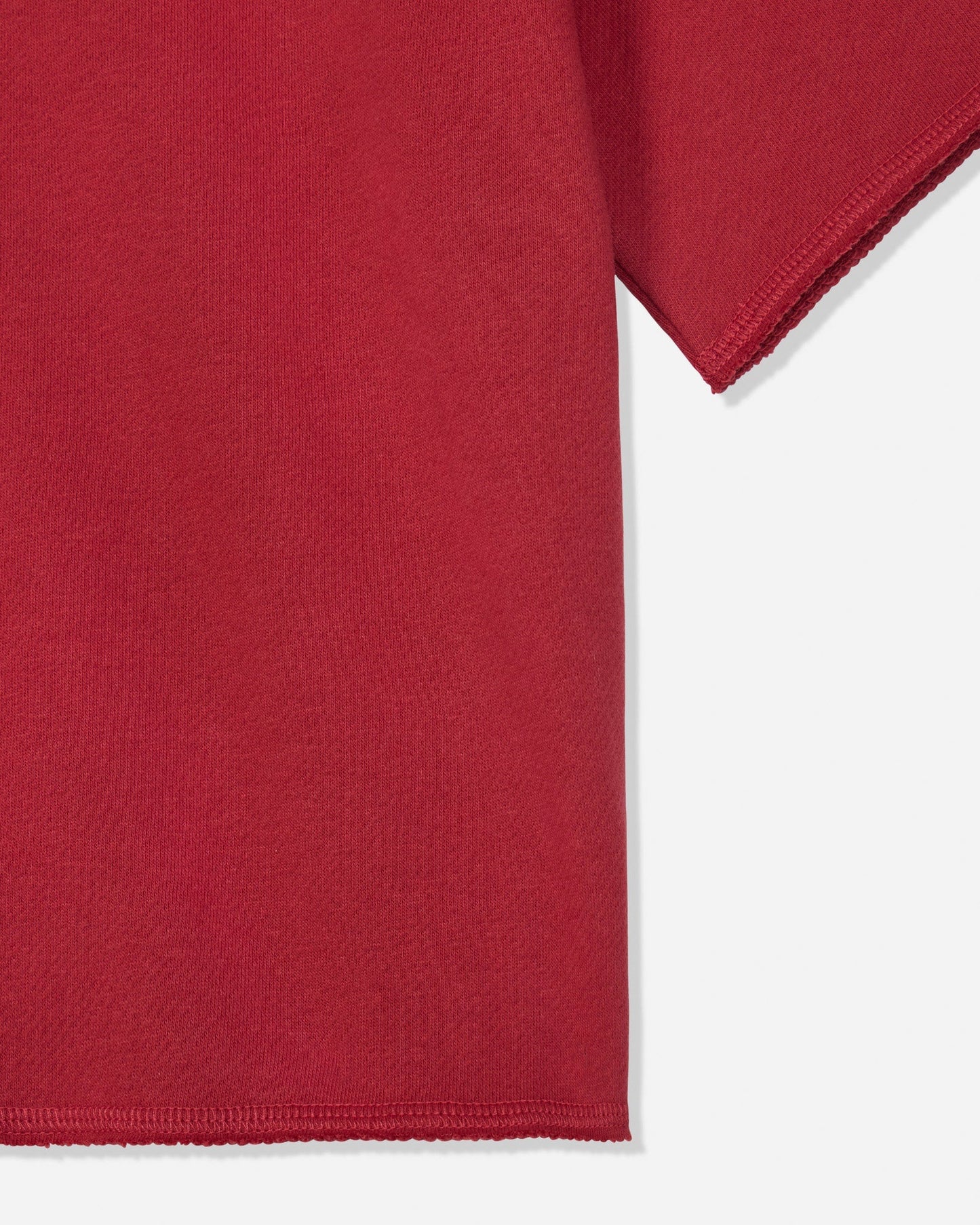 Close-up of a red short-sleeve garment showing the sleeve and hem against a light gray background.#color_tomato