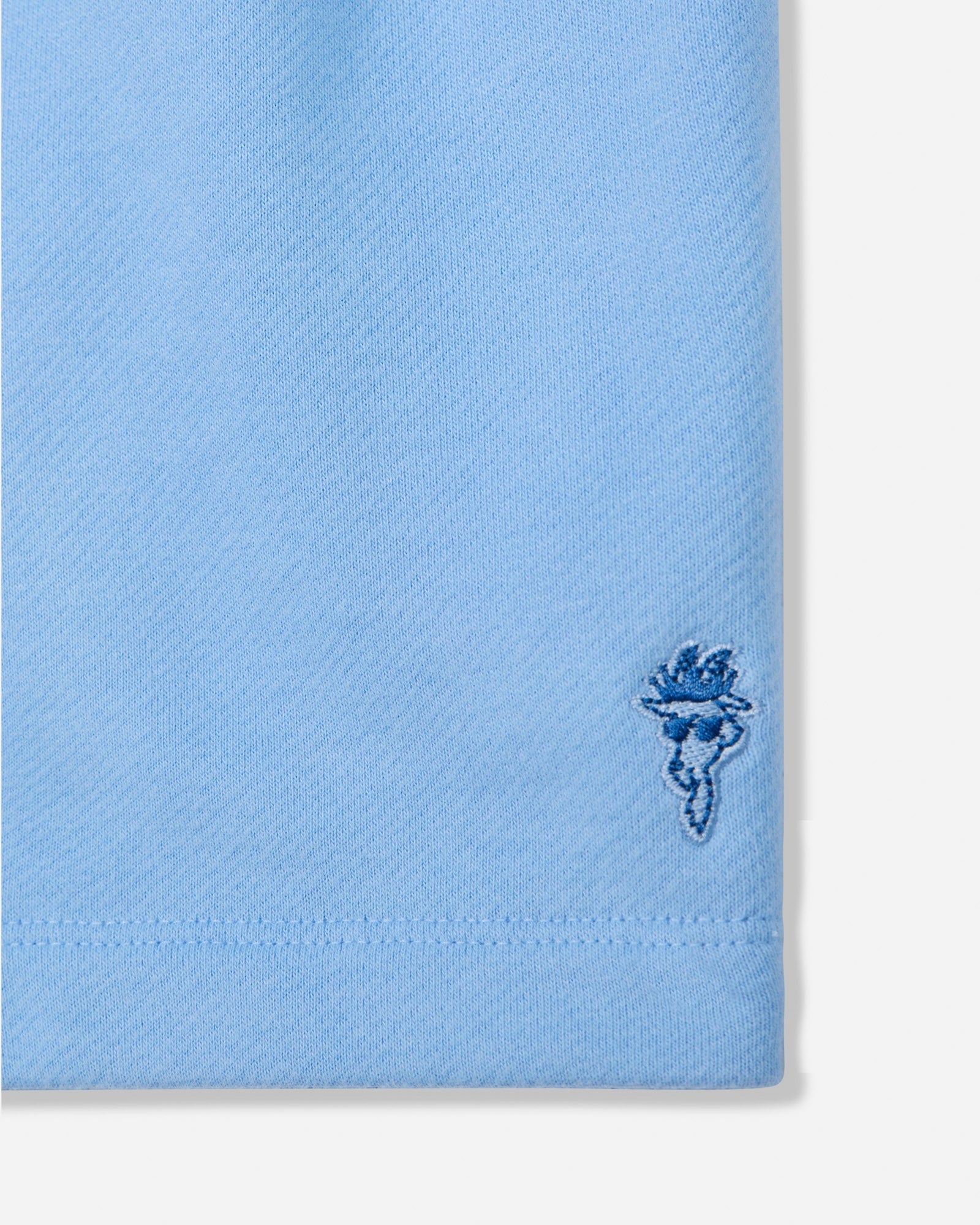 Close-up of carolina blue sweat shorts with goat head patch#color_carolina-blue