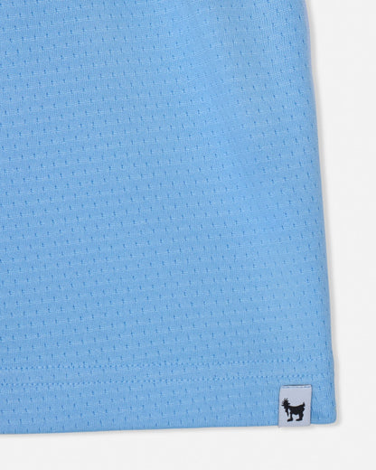 Close-up of a blue textured fabric with a brand label on a white background#color_carolina-blue