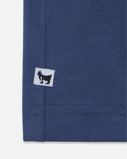 Close-up of a blue fabric with a small white label featuring a black logo on a white background#color_navy