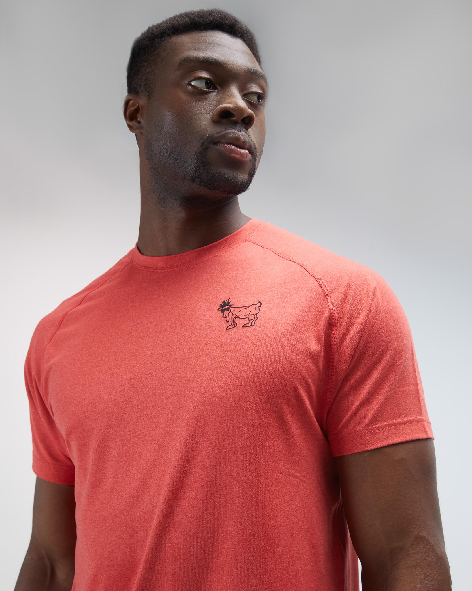 Man wearing a red t-shirt with a small logo on a gray background#color_poinsettia
