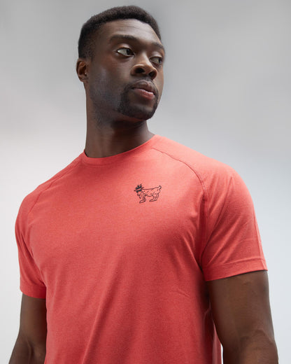 Man wearing a red t-shirt with a small logo on a gray background#color_poinsettia