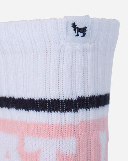 Close-up of a white ribbed knit sock with a black horizontal stripe and a pink graphic pattern at the bottom, featuring a small black goat logo on a white tag at the cuff.#color_pink