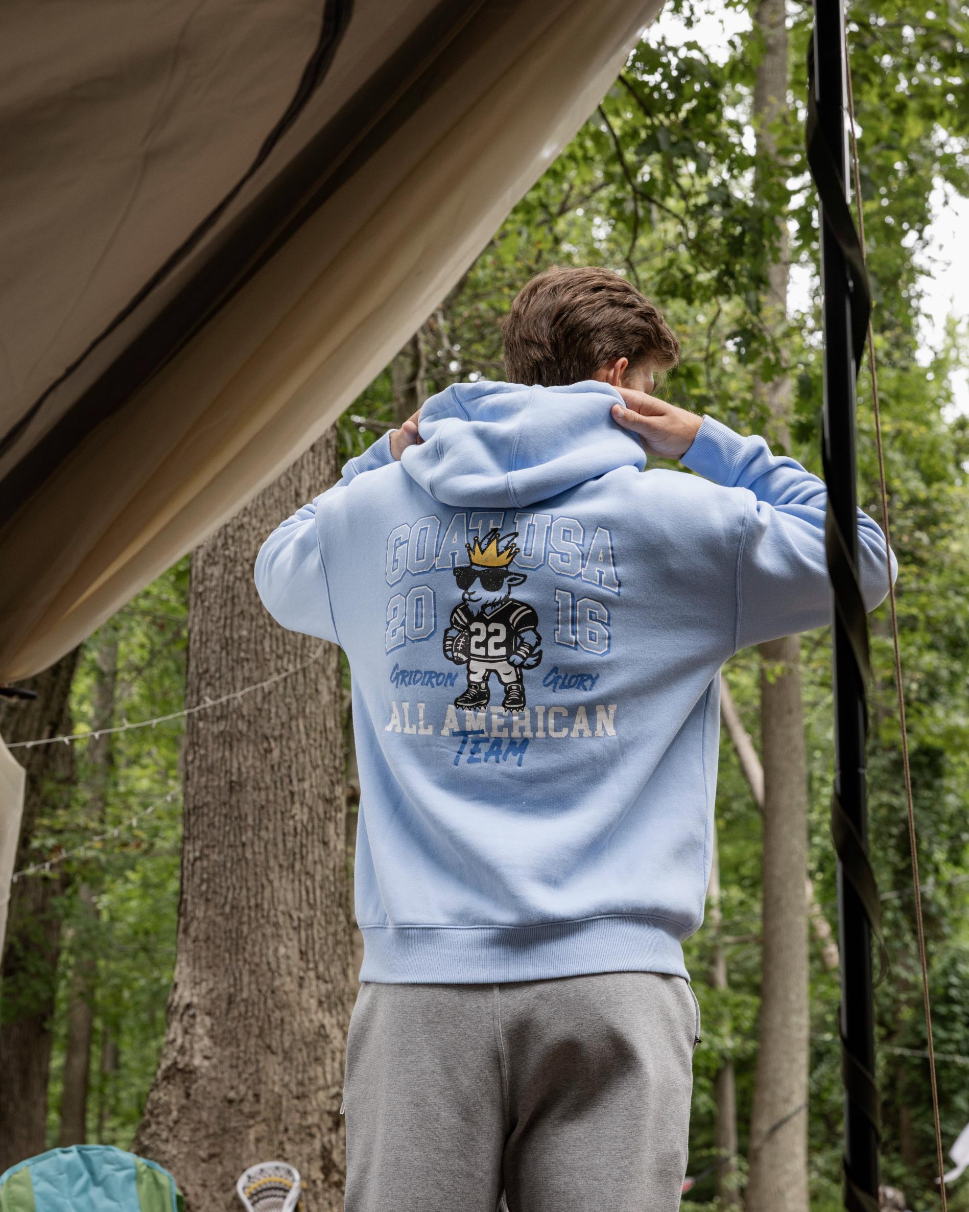 Person wearing a light blue hoodie with text and graphics in a forest setting