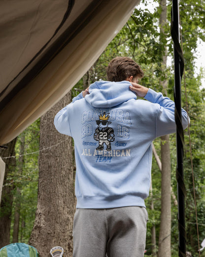 Person wearing a light blue hoodie with text and graphics in a forest setting