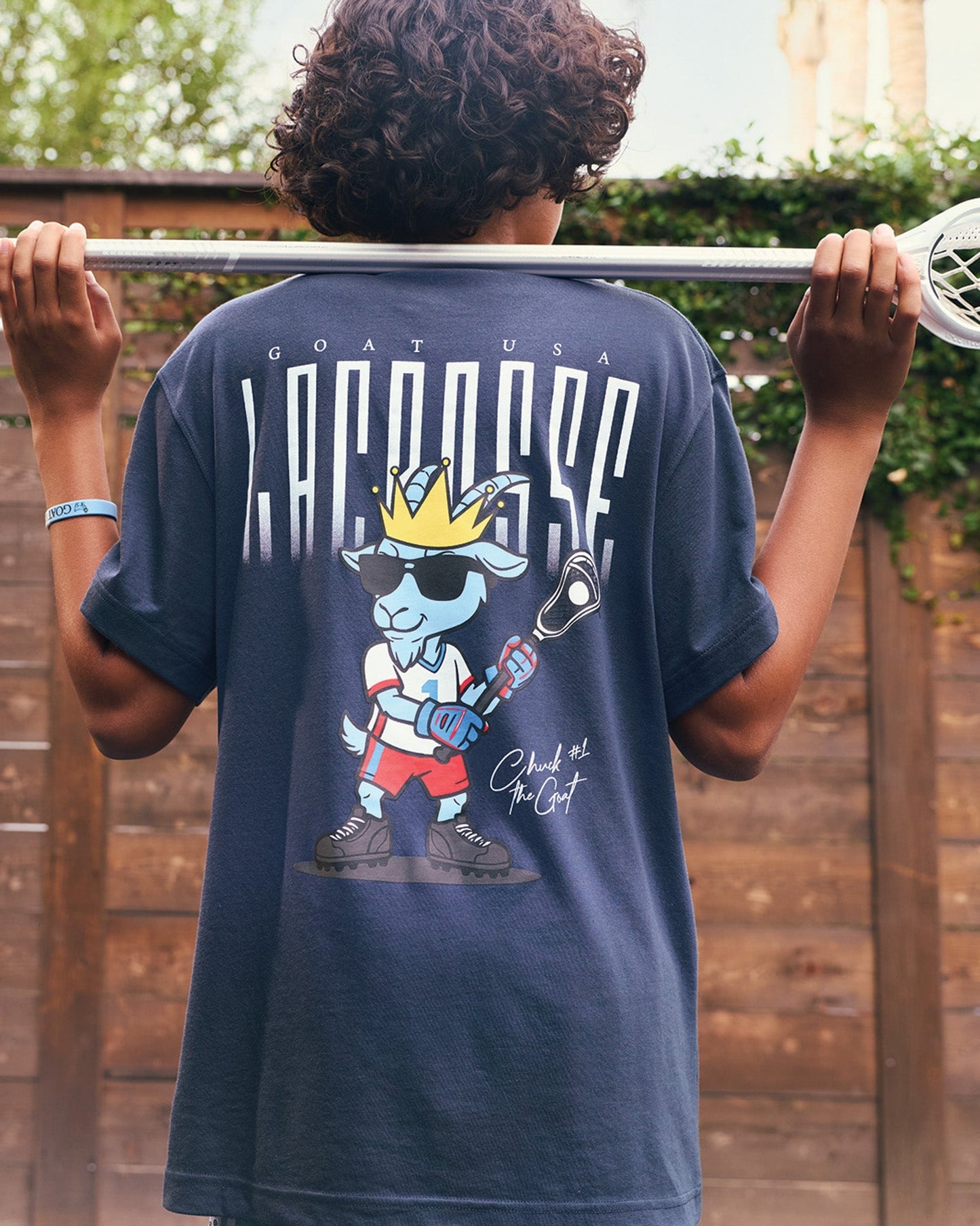 Person wearing a navy blue t-shirt with a graphic design on the back, standing outdoors.