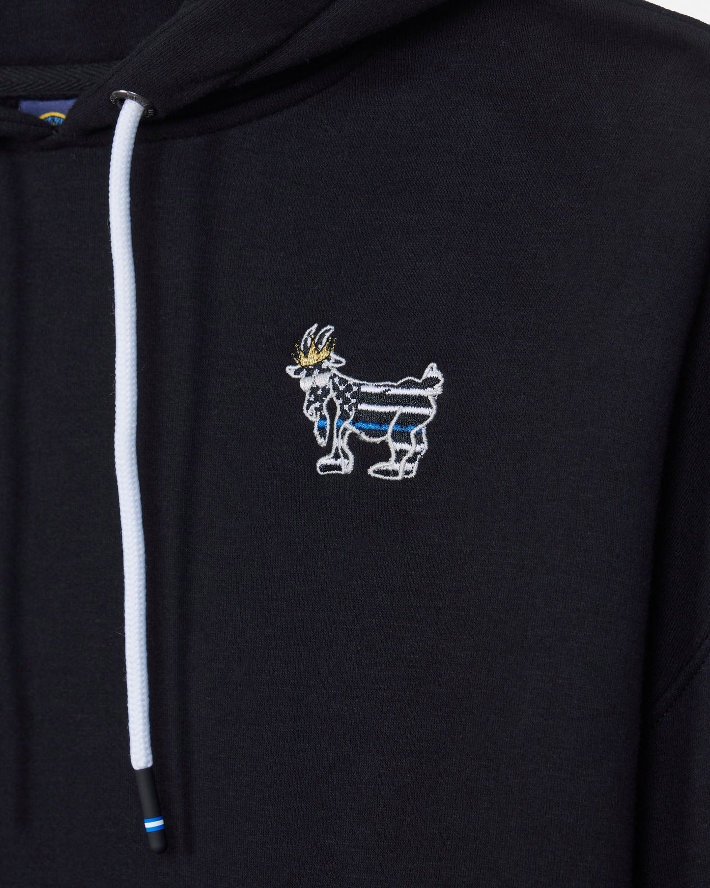 Close-up of a black hoodie featuring a white drawstring and a small embroidered goat mascot logo on the left chest, with blue and gold details.