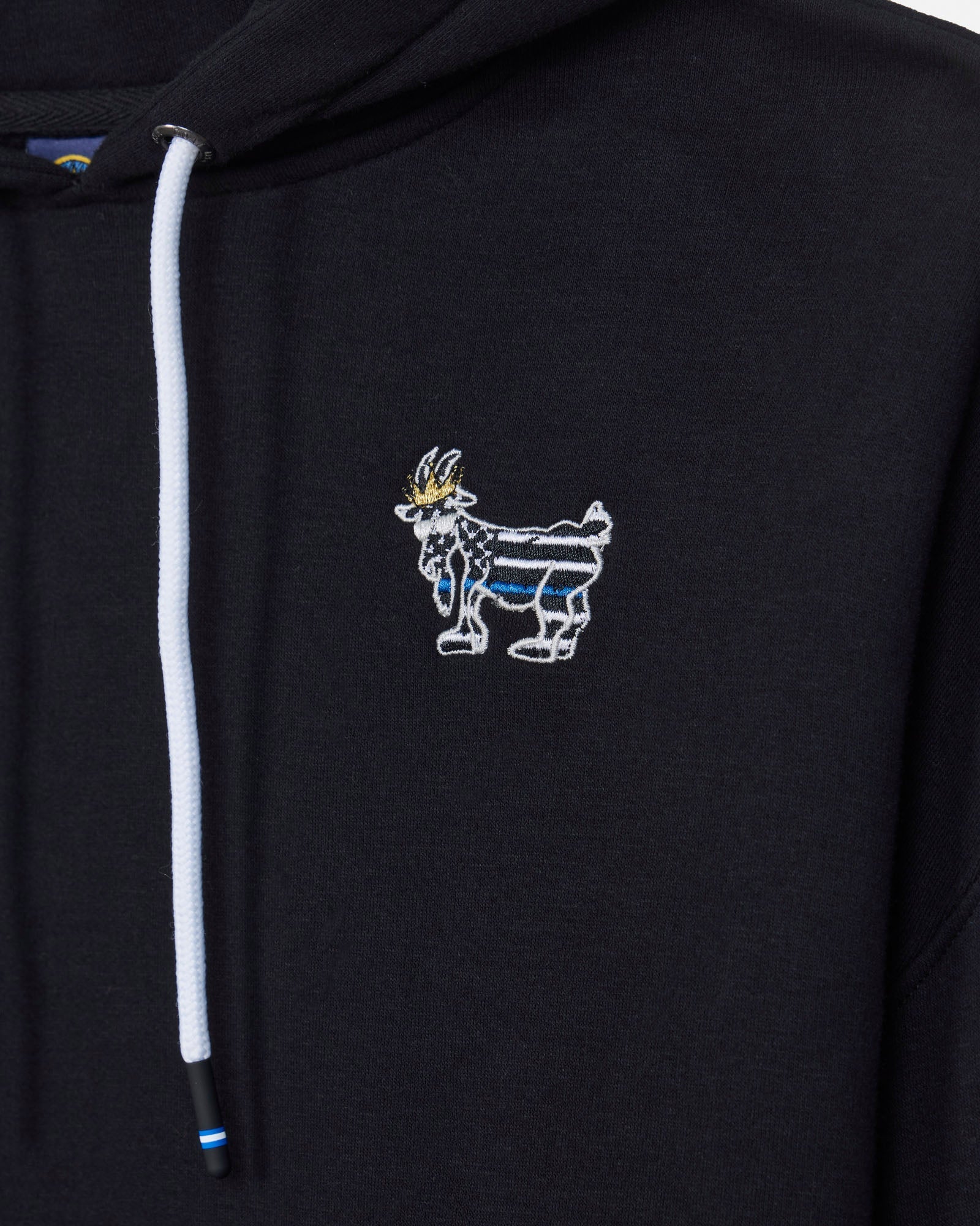 Close-up of a black hoodie featuring a white drawstring and a small embroidered goat mascot logo on the left chest, with blue and gold details.