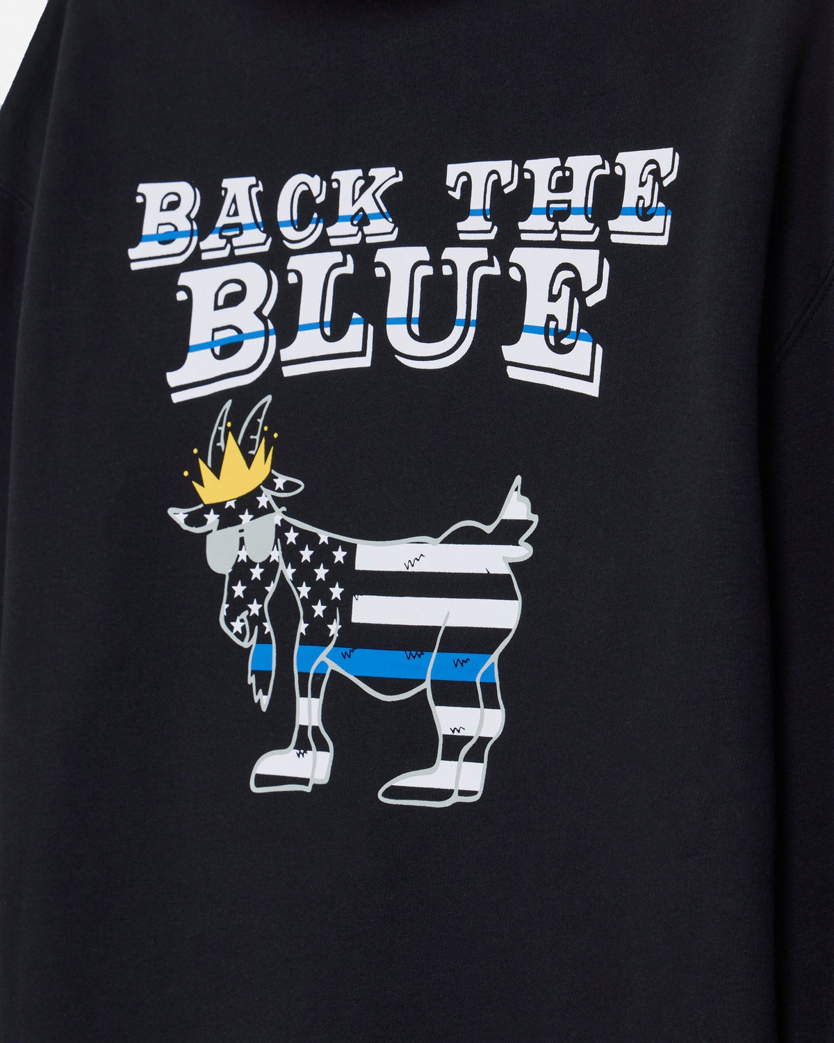 Close-up of a black sweatshirt featuring a graphic print that reads 'BACK THE BLUE' above a stylized goat filled with a U.S.