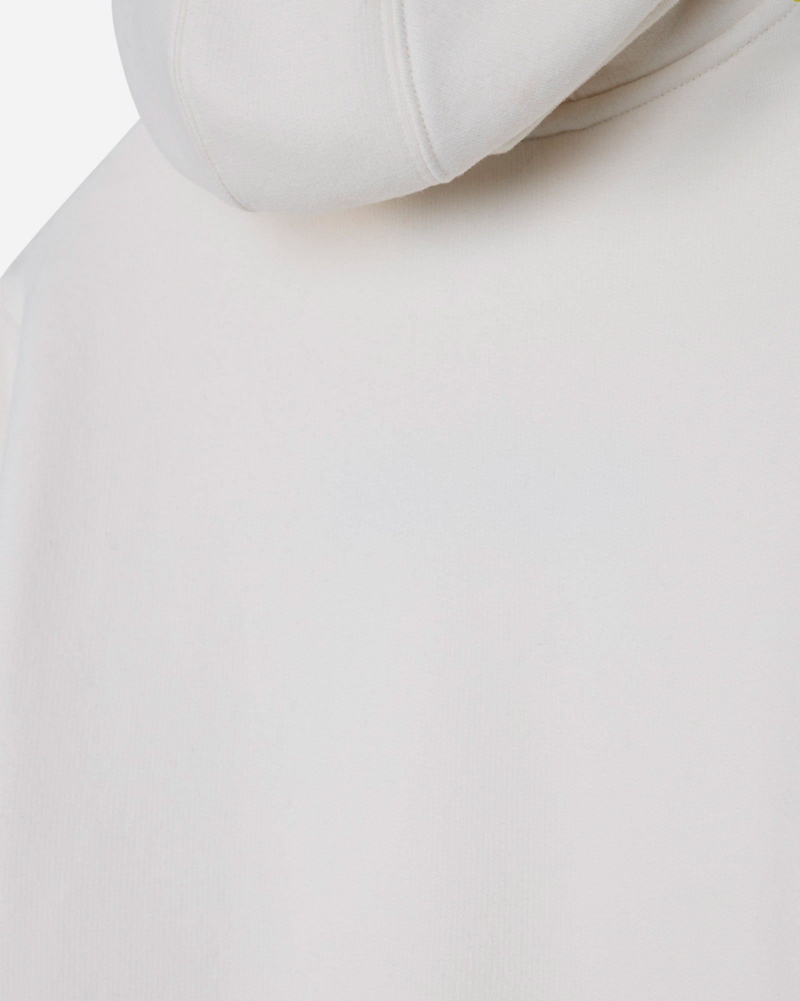 Close-up of a light off-white or cream-colored hoodie, showing the smooth fabric texture and the edge of the hood.