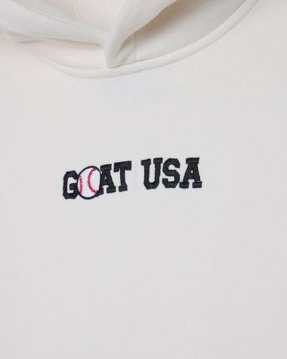 Close-up of a white hoodie featuring an embroidered 'GOAT USA' logo on the chest, with the letter 'O' stylized as a baseball.