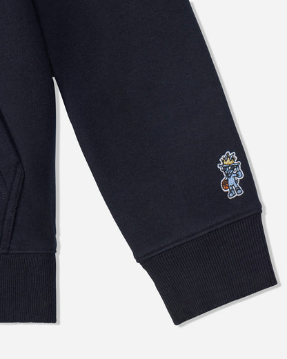 Close-up of a black sweatshirt sleeve with a ribbed cuff and a small embroidered cartoon character on the upper cuff, shown against a light gray background.