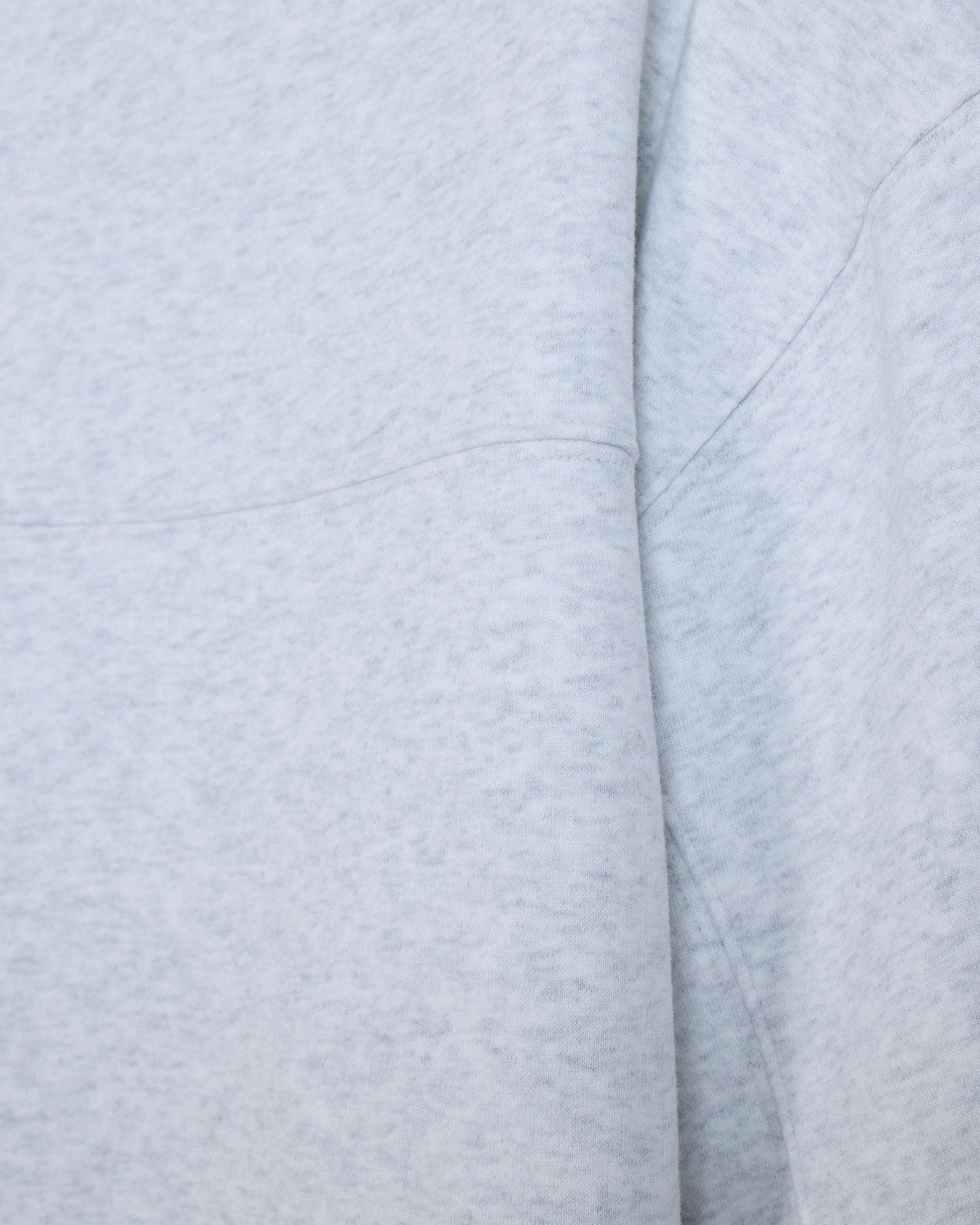 Close-up of a light heather gray fabric with soft folds and stitched seams.