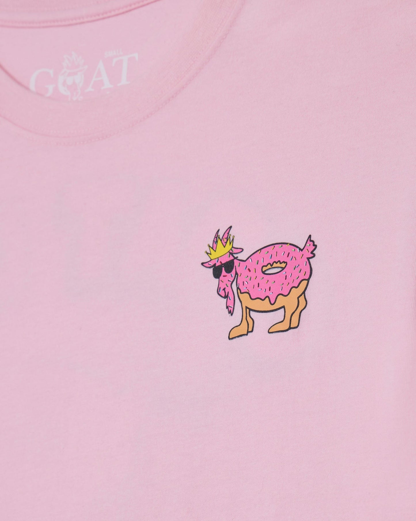 Pink t-shirt with a cartoon goat wearing a crown and sunglasses, and the brand 'GOAT USA' on a pink background.