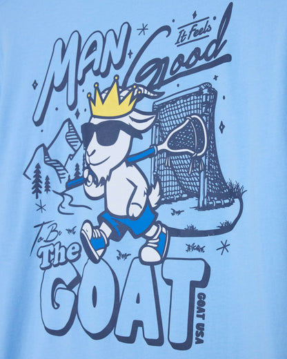 T-shirt design with a cartoon goat wearing a crown, holding a lacrosse stick, and text on a light blue background.