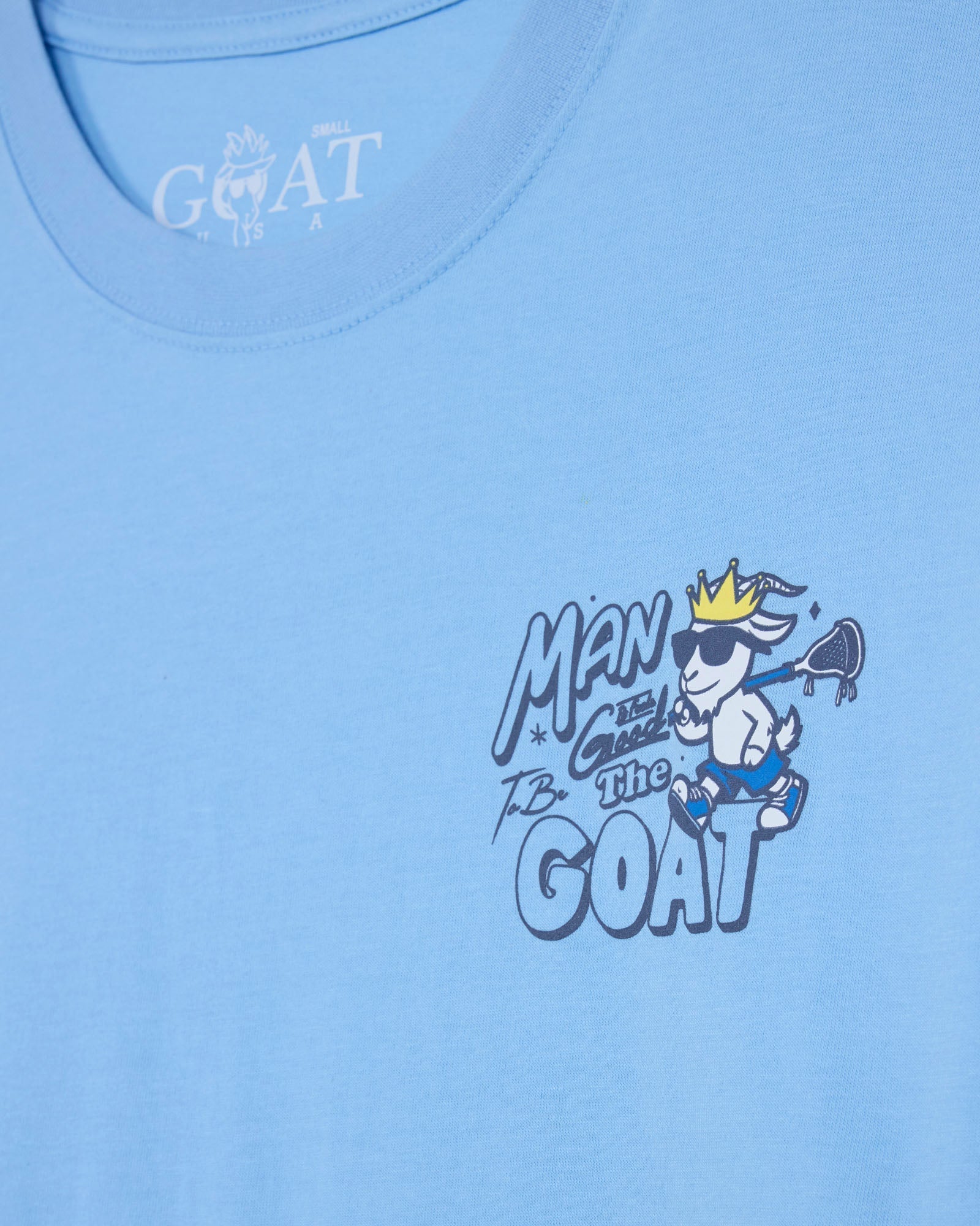 Light blue t-shirt with a graphic of a goat wearing sunglasses and a crown on a light blue background.