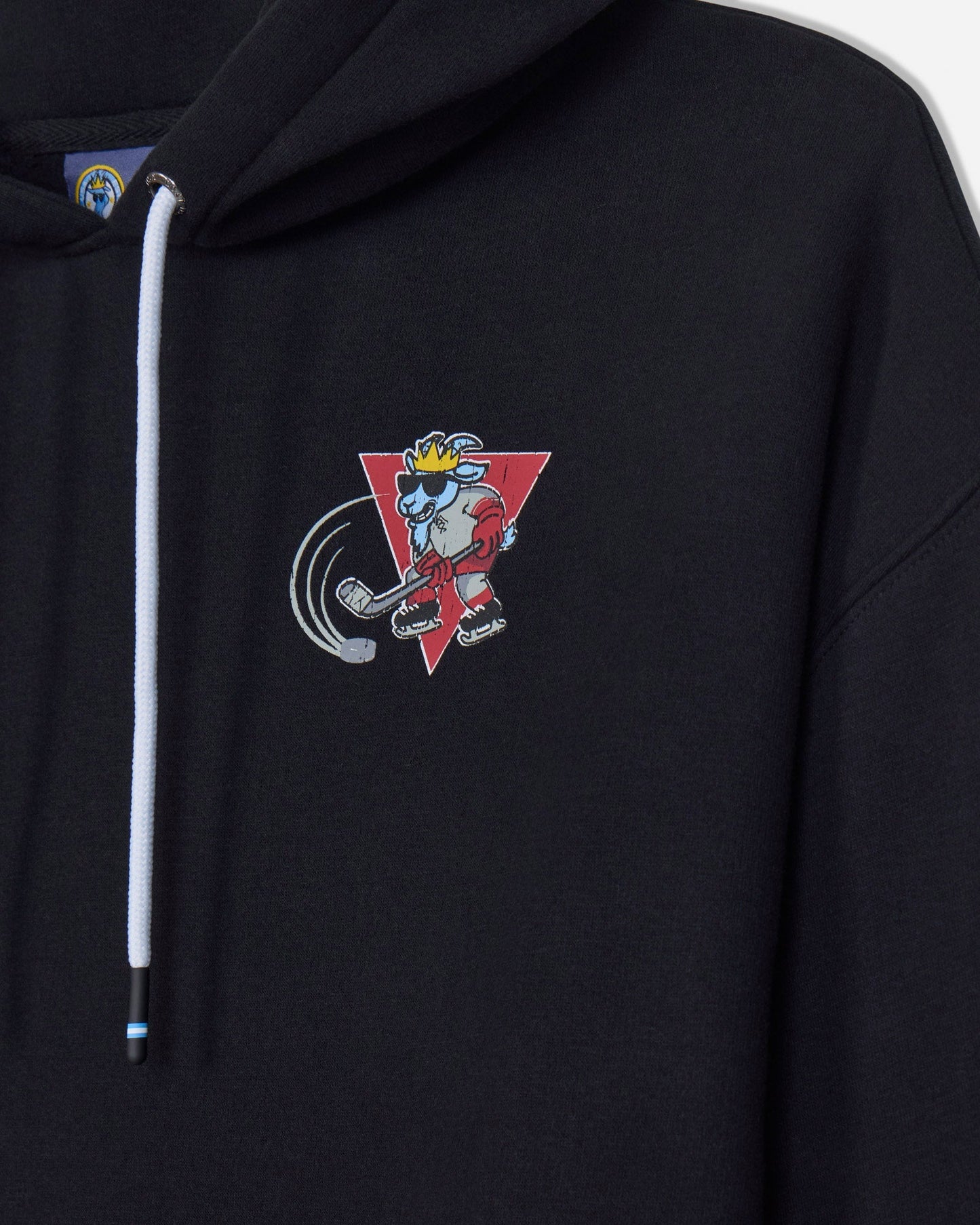 Close-up of a black pullover hoodie with a white drawstring and a colorful cartoon graphic on the left chest, featuring a red triangle and a character in a yellow crown.