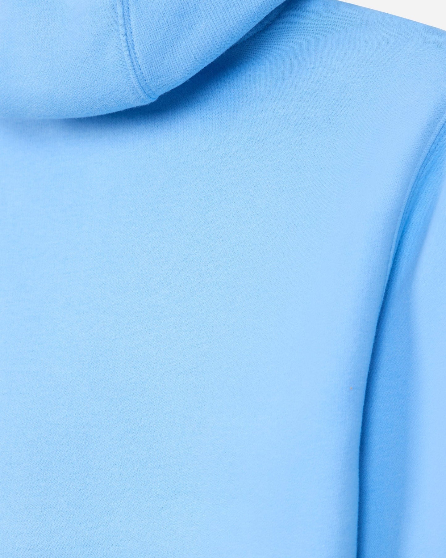 A close-up of a light blue hooded sweatshirt showing the smooth fabric texture, hood seam, and shoulder area.