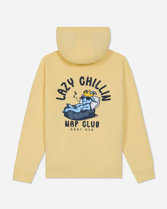 A pale yellow hooded sweatshirt shown from the back, featuring a large graphic print of a sleeping cartoon character on a bed with the text 'LAZY CHILLIN' and 'NAP CLUB' in black.