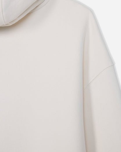 Close-up of a light cream or off-white hooded sweatshirt, showing the smooth fabric texture, hood edge, and shoulder seam against a very light neutral background.#color_bone