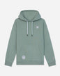 A sage green pullover hoodie with white drawstrings, featuring a small white goat graphic on the left chest and a circular patch on the lower left front pocket, displayed against a light gray background.#color_steeped-sage