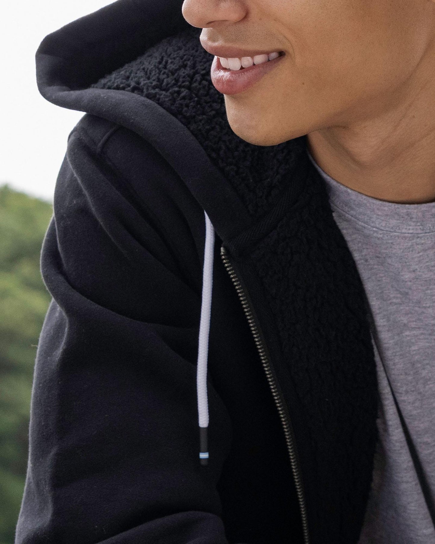 Person wearing a black hoodie with a blurred background#color_black