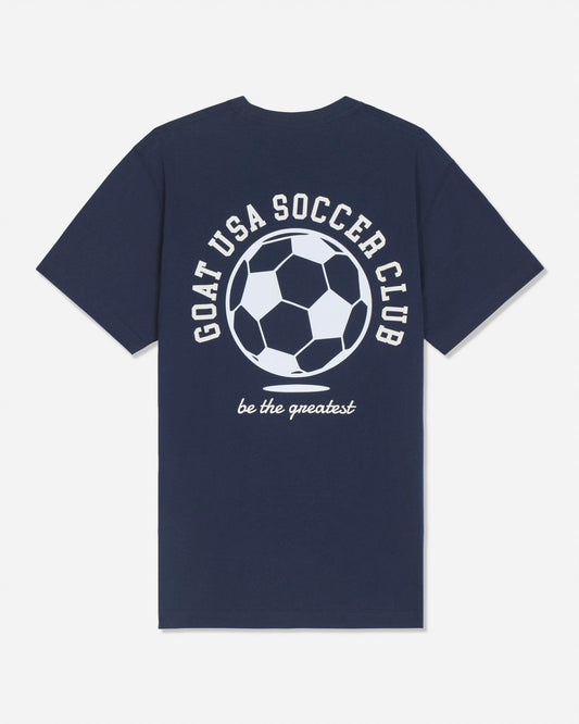 A navy blue short-sleeve t-shirt with a white graphic on the back featuring a soccer ball and the text 'GOAT USA SOCCER CLUB' and 'be the greatest'.