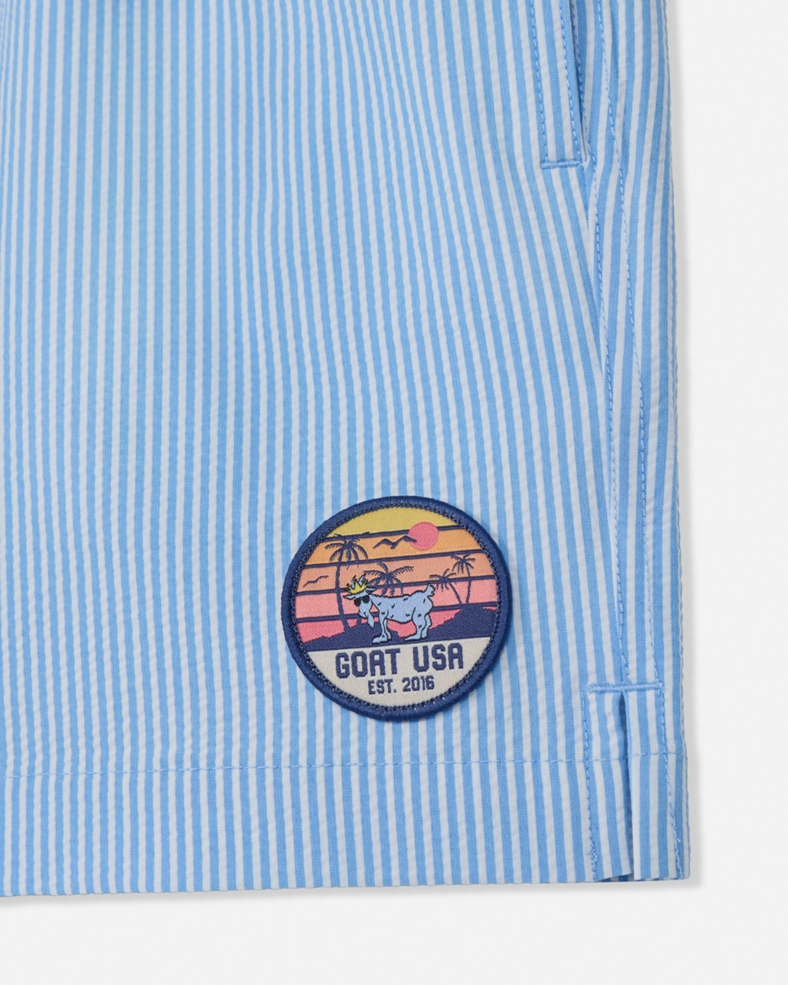 Blue and white striped shirt with a circular patch featuring a cow and sunset design.