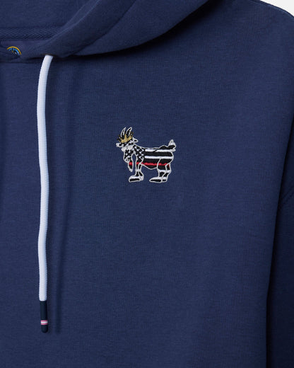 Close-up of a navy blue hoodie featuring a white drawstring and a small embroidered goat graphic on the chest with red, white, and black stripes and a gold crown.
