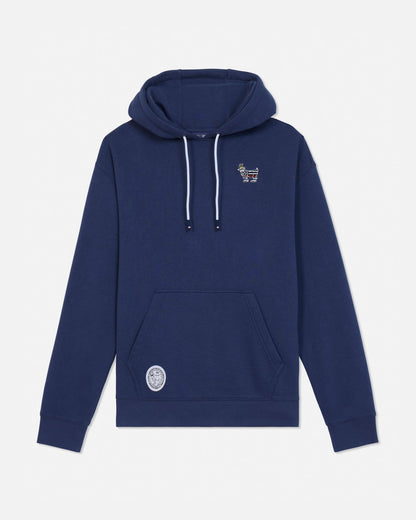A navy blue pullover hoodie with white drawstrings, featuring a small embroidered graphic on the left chest and a circular patch on the lower left front pocket, displayed against a light gray background.