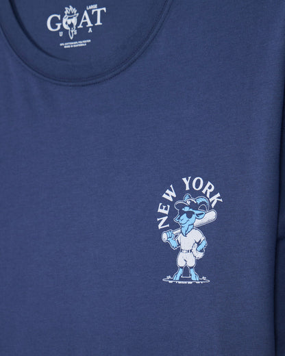 Close-up of a blue short-sleeve t-shirt featuring a light blue and white New York-themed cartoon graphic on the left chest with the text 'NEW YORK' arched above it.